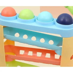 Close-up of blue hammering toy top with colored balls and orange rails.