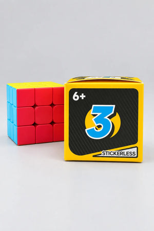 Stickerless 3x3 cube beside yellow packaging marked ages 6+ and stickerless