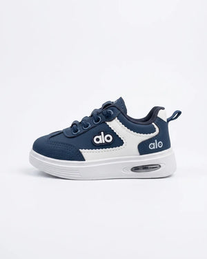 Blue Alo kids sneakers worn with light trousers, showing side detail and white soles