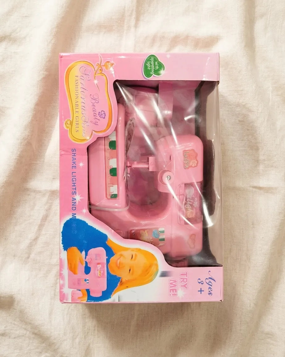 Kids pink toy sewing machine in retail box, clear window