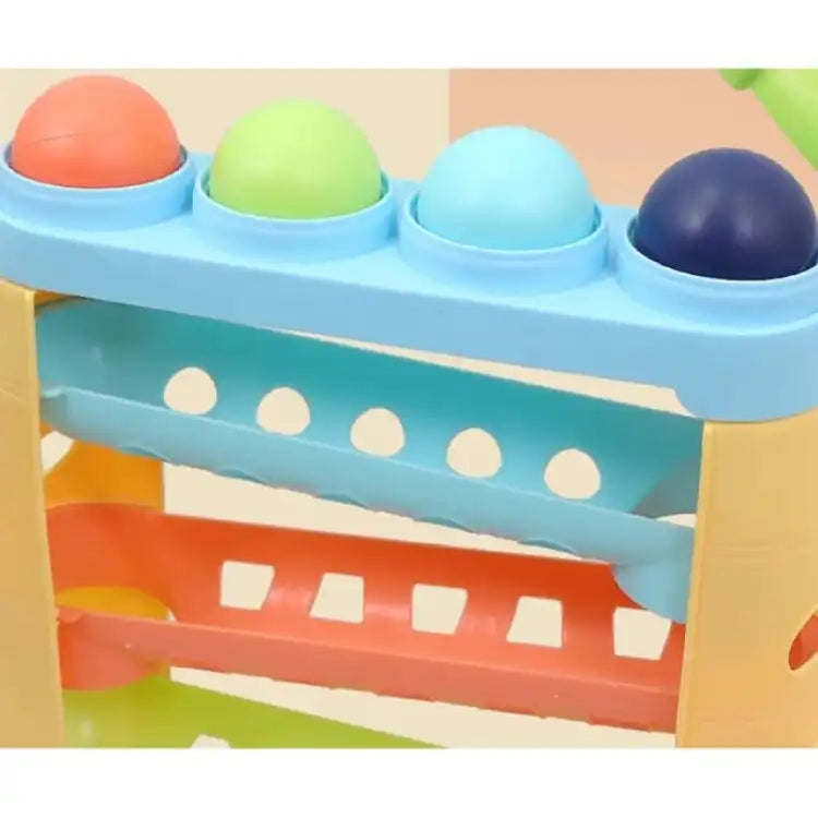 Close-up of blue hammering toy top with colored balls and orange rails.