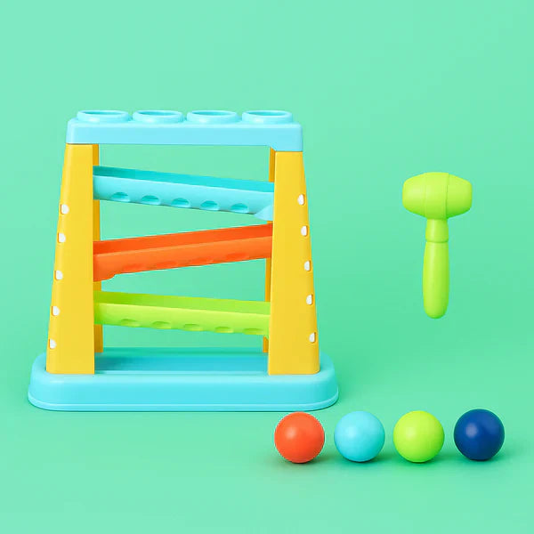 Hammering toy with blue base frame, green mallet, and four balls on floor.