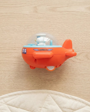 Orange mini airplane toy with clear dome cockpit and snowman pilot figure, side view.