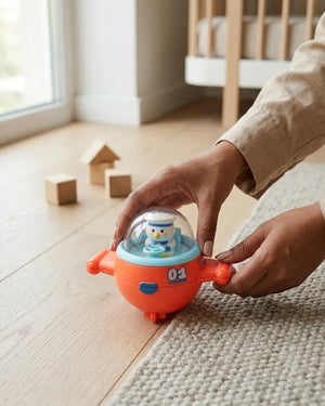 Mini orange airplane toy with clear dome cockpit and snowman pilot, held by hand.