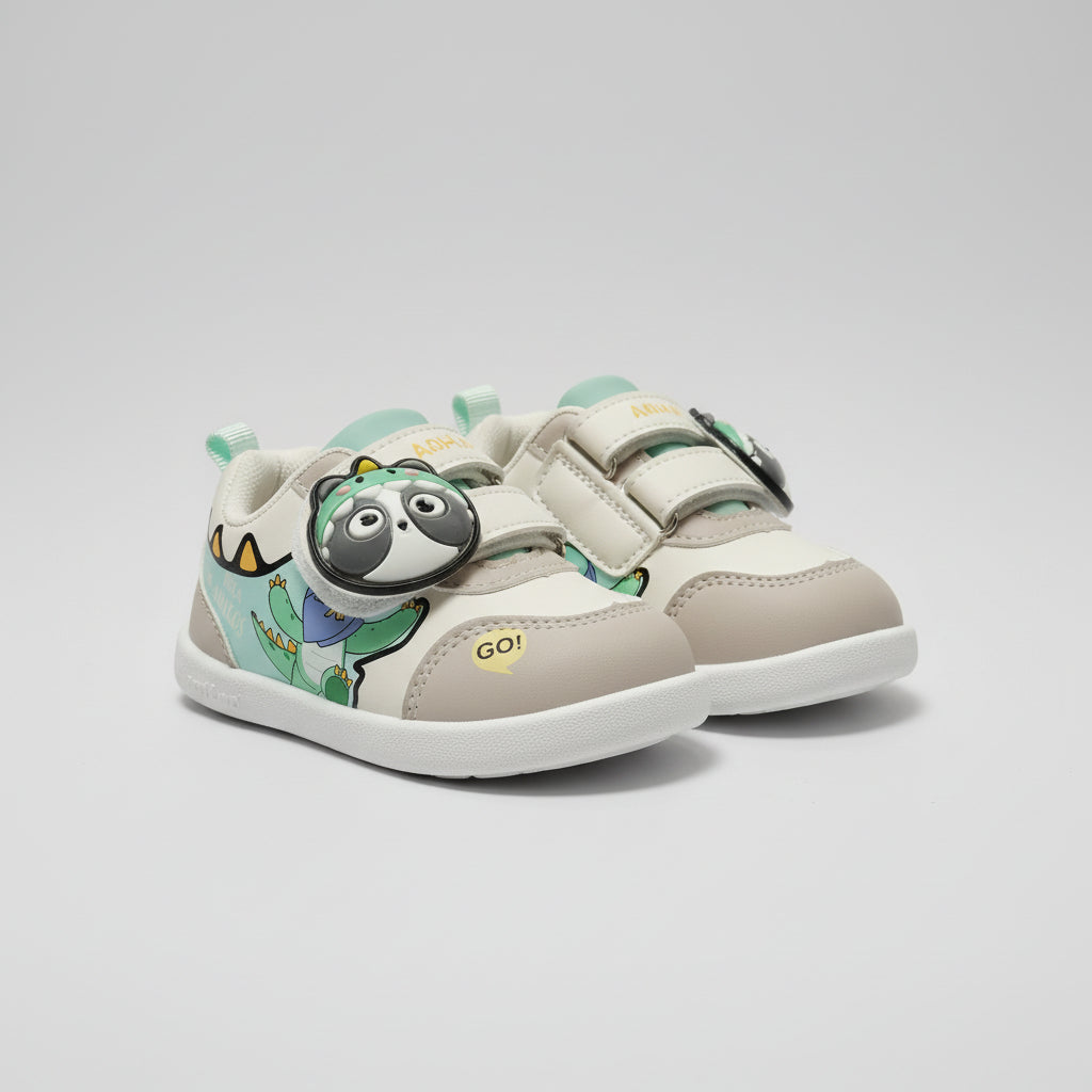 A pair of toddler's lace-up sneakers with a cartoon dinosaur and panda design, displayed on a store counter.