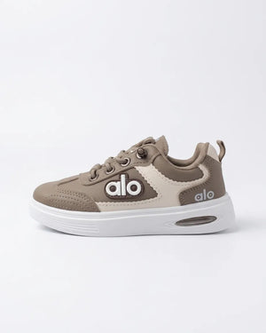 Beige Alo kids sneaker worn, showing contrast side panels, lace-up front and white chunky sole