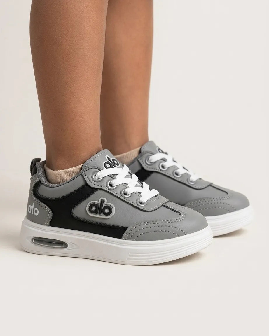 Pair of grey Alo kids sneakers from the front showing laces, stitched toes and white soles