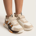 Child wearing beige TrailPop strap sneakers with orange and brown side accents