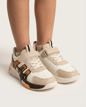 Child wearing beige TrailPop strap sneakers with orange and brown side accents