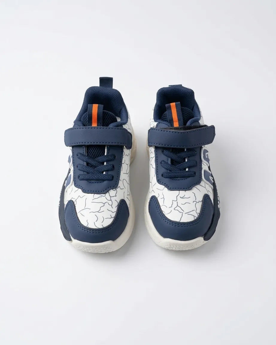 Beige kids strap sneaker in profile showing brown and orange side detail