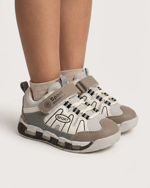 Angled side view of beige and grey kids sneaker showing strap, elastic-style laces and textured sole