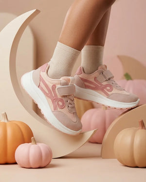 Pink girls' sneakers with lace-up front, strap and white chunky sole worn on foot