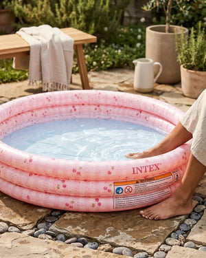 Pink round inflatable kids swimming pool with water, side with safety warning labels