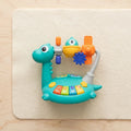 Kids dinosaur cartoon hand-crank piano toy with teal keyboard and crank handle