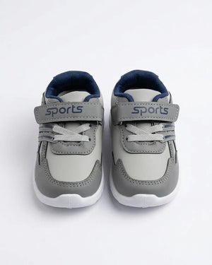 Grey kids sports sneakers shown from the front with lace detail and straps