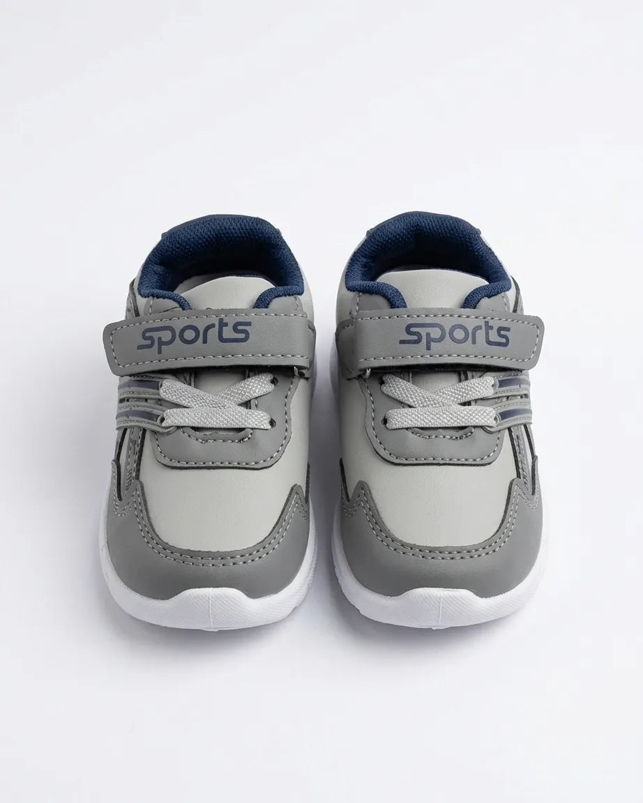 Grey kids sports sneakers shown from the front with lace detail and straps