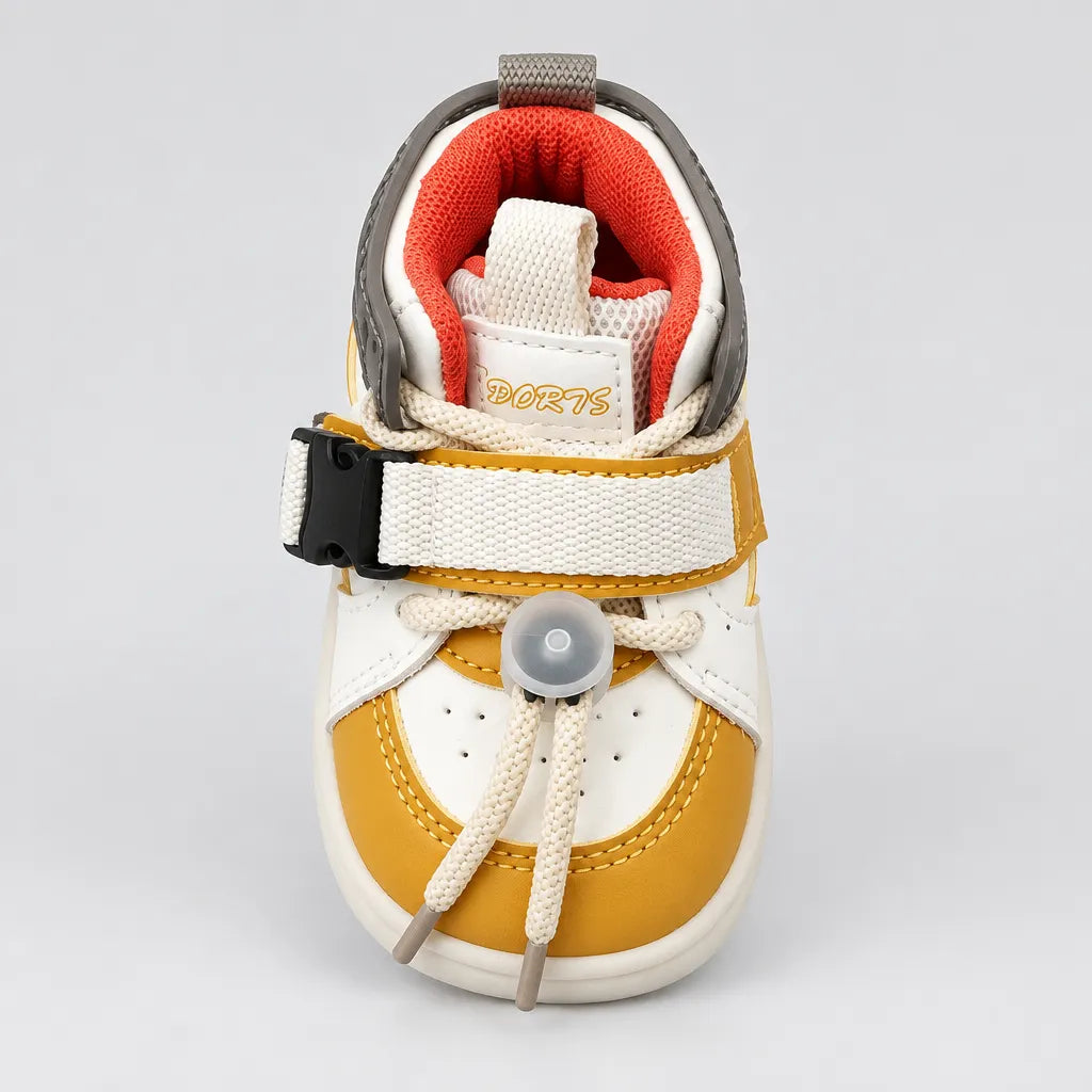 A baby's first shoe featuring a white and mustard yellow color-blocked design, with beige laces tied in a bow, a hook-and-loop strap with a black plastic buckle, and a soft orange inner lining. The brand name 'PORTS' is visible on the tongue label.
