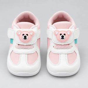 Back view of a pink and white kids’ sneaker with a mesh-textured collar.