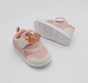 Light pink kids' sneakers showing textured white outsole with circular bear logos