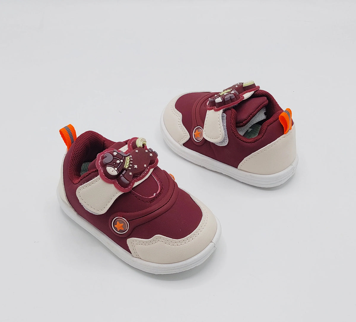 Deep burgundy and beige kids' sneakers with bear strap detail and orange lace loops