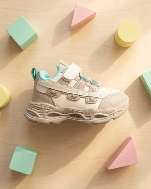 Beige and cream kids chunky sneakers with mint accents worn by a child