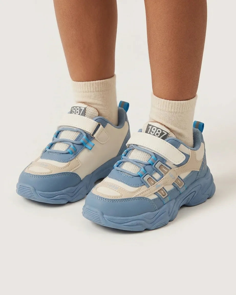 Blue and cream kids chunky sneakers, front view showing straps and elastic-style laces