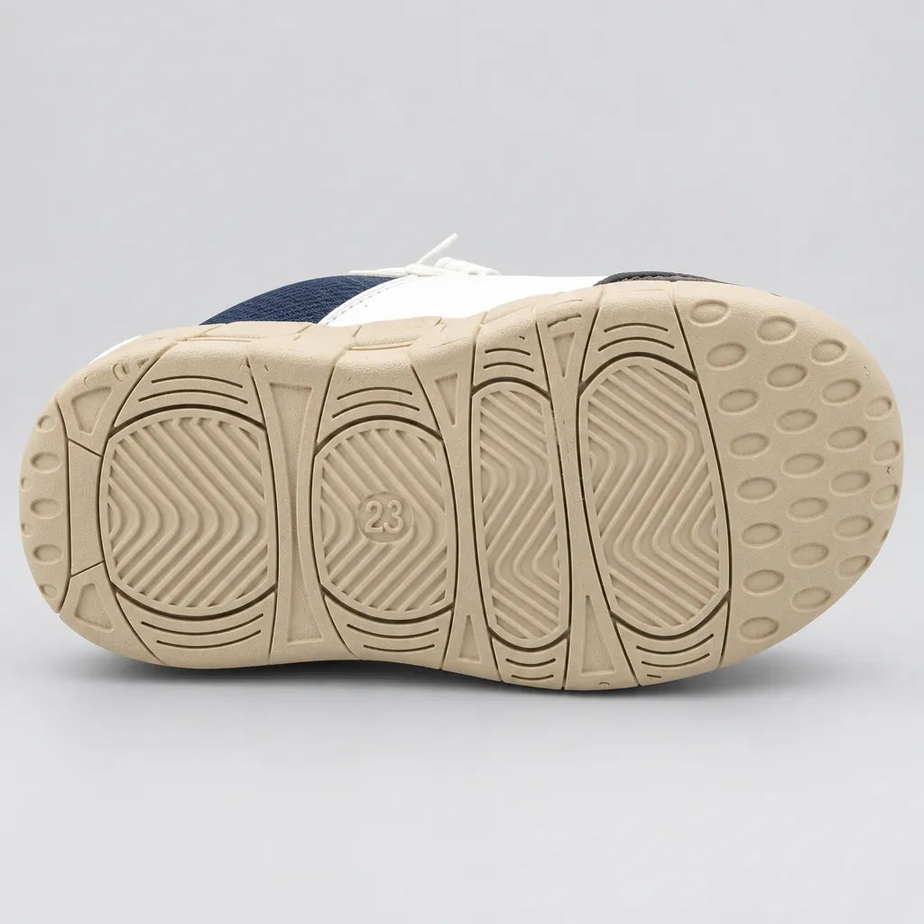 Side view of navy and white kids sport sneaker with strap and chunky beige sole