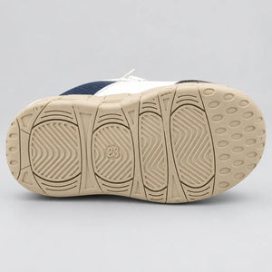 Side view of navy and white kids sport sneaker with strap and chunky beige sole