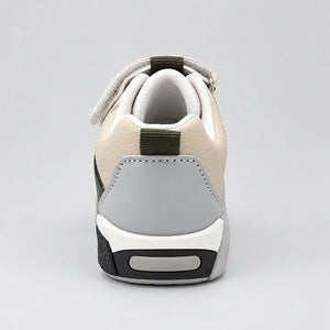Rear view of a beige kids sneaker showing the grey heel panel, padded collar and dark green pull tabs