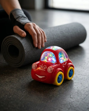Red flashing toy bump car with colorful lights on a gray floor near a yoga mat