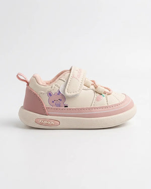 Child wearing cream and tan cartoon sneakers with hook-and-loop strap