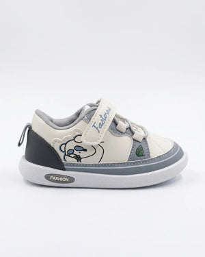 Child wearing cream and grey cartoon sneakers with strap fastening