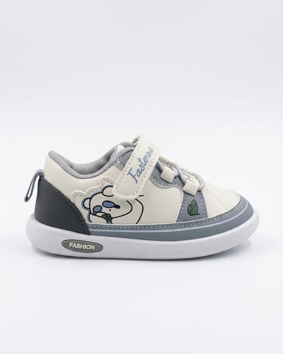 Child wearing cream and grey cartoon sneakers with strap fastening