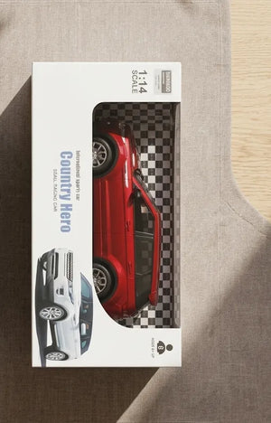 Red RC car in retail blister box, viewed from above on surface.