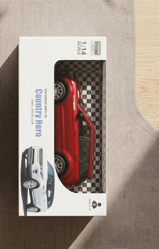 Red RC car in retail blister box, viewed from above on surface.