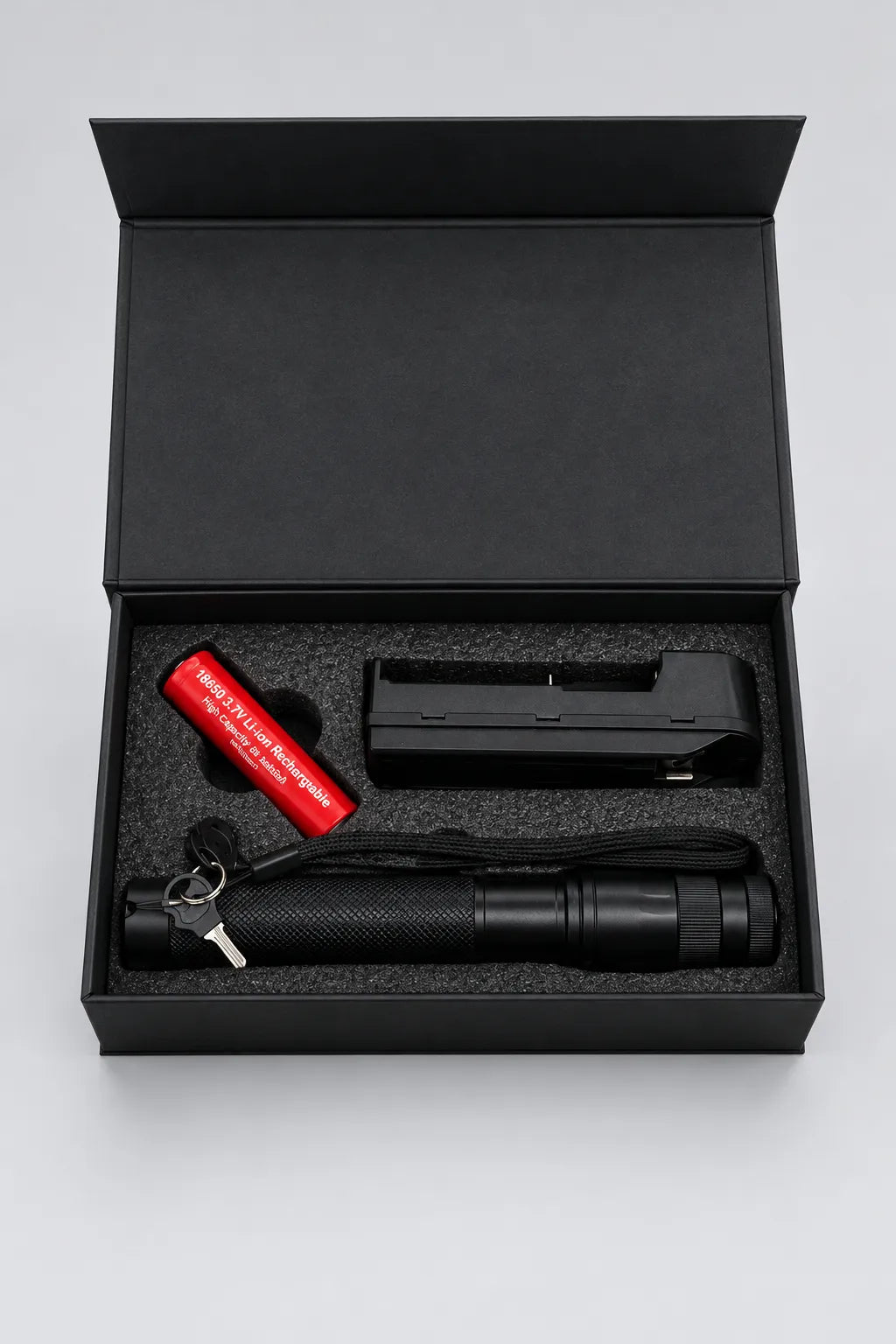 Green laser pointer kit in an open black box with rechargeable battery, charger, keys and wrist strap